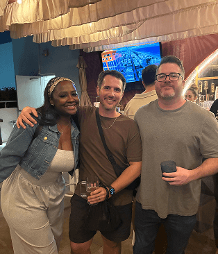 3 people smiling in front of a bar