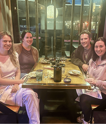 4 people smiling seated at a restaurant booth table