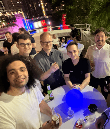 5 people with drinks smiling on the top deck of a yacht