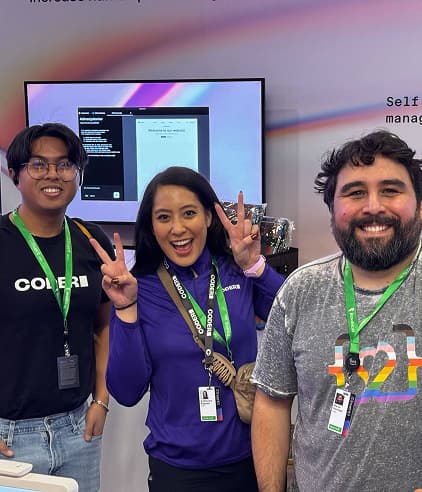 3 people smiling wearing green lanyards at a Coder event